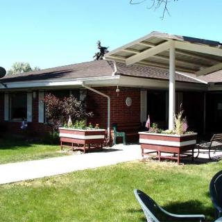 A backyard view of a house featuring a patio with outdoor furniture and garden planters.