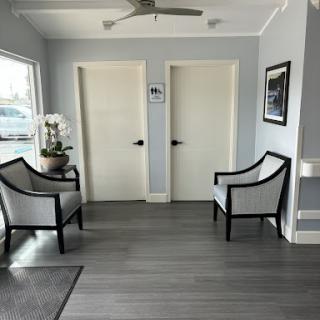 A modern waiting area featuring stylish chairs, two doors, and a touch of greenery.