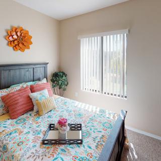 A cozy and colorful bedroom with floral bedding and a sunlit window.