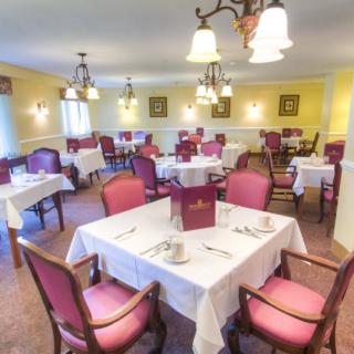 An elegant dining room with neatly arranged tables and chairs, set for a meal.