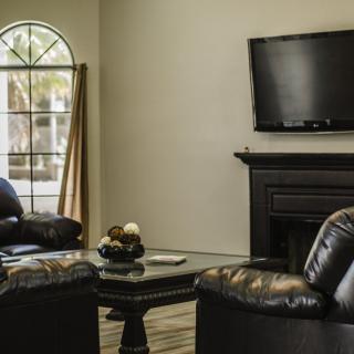 A cozy living room with leather chairs, a fireplace, and a mounted television.