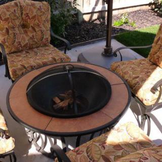 A cozy outdoor patio setup featuring a firepit surrounded by cushioned chairs, perfect for gatherings.