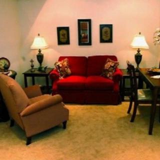 A cozy living room with a red sofa, armchair, and elegant lighting.