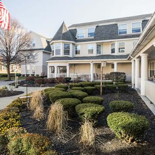 A well-maintained building with manicured bushes and an American flag in the garden.