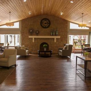 A cozy living room with a wood ceiling, featuring a central fireplace and comfortable seating.