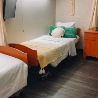 A hospital room with two neatly made beds and a dresser.