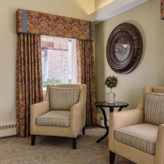A cozy living room with two armchairs, a side table, and decorative curtains.