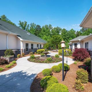 Beautifully landscaped courtyard with buildings and a central pathway surrounded by shrubs and trees.