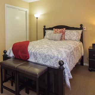 A cozy and well-decorated bedroom with a neatly made bed, bedside lamps, and a nightstand.