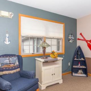 A cozy living room with nautical-themed decor, featuring a blue armchair, decorative sailboat, and anchor embellishments.