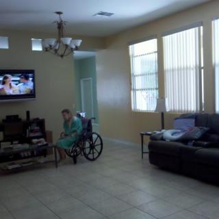 A person in a wheelchair watching TV in a living room.