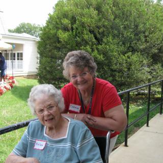 Two women enjoying a sunny day in the garden, with one seated in a wheelchair.