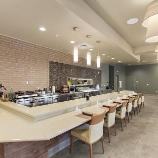 A modern restaurant interior featuring a long bar counter with seating and contemporary lighting.