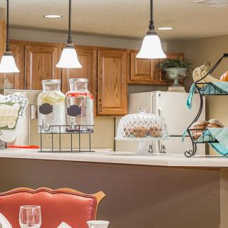 A cozy kitchen interior with wooden cabinets, decorative lighting, and a variety of countertop items.