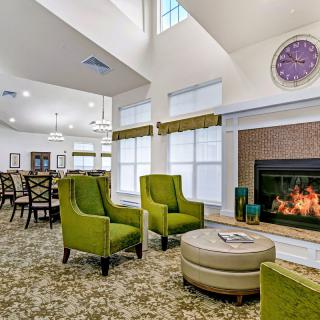 A modern living room with green chairs and a fireplace, featuring cozy and stylish decor.