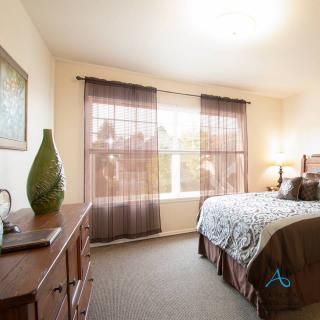 A cozy bedroom with natural light from a large window and stylish decor.
