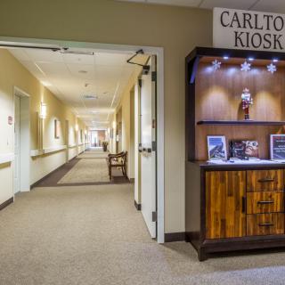 A well-lit interior hallway featuring a kiosk display labeled 'Carlton Kiosk'.