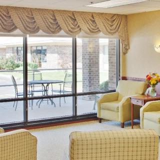 A cozy living room with comfortable chairs and a view of a patio through large windows.