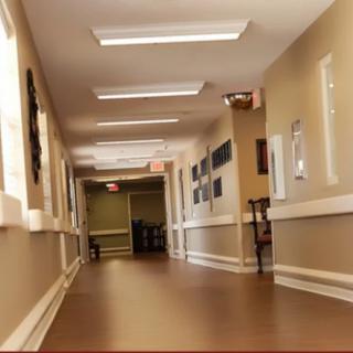 A well-lit, empty hallway with brown flooring and framed pictures on the walls.