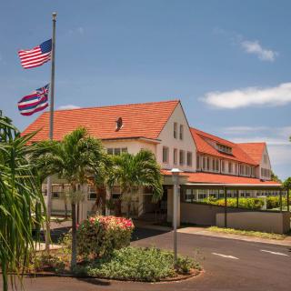 A tropical building with a red roof and American flag on display under a clear sky.