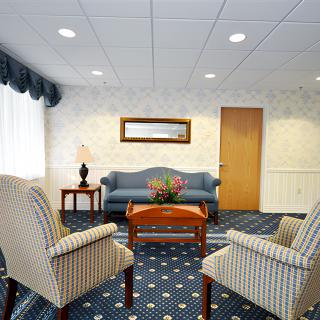 A cozy waiting room with a sofa, armchairs, and a central table.