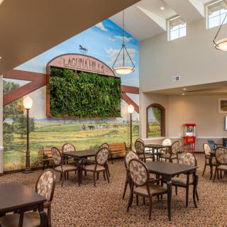A bright and welcoming cafe interior with tables, chairs, and decorative wall art.