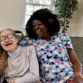 A joyful moment shared between an elderly resident and her caregiver, capturing the essence of companionship and care.