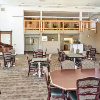 A spacious dining area with multiple tables and chairs, featuring bright lighting and a loft overhead.