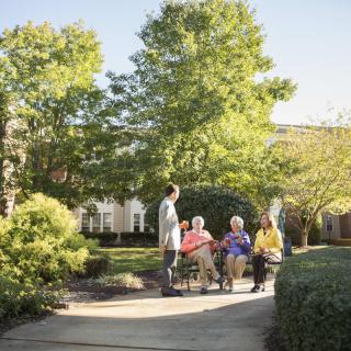 A group of seniors enjoying a conversation in a beautiful garden setting.