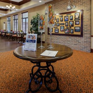 A cozy restaurant interior with a central table displaying brochures, surrounded by framed pictures and warm lighting.