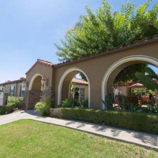 A building with arched entrances surrounded by a well-maintained garden and lawn.