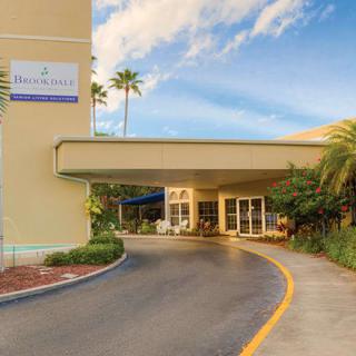 Hotel entrance with a driveway surrounded by palm trees and landscaping.