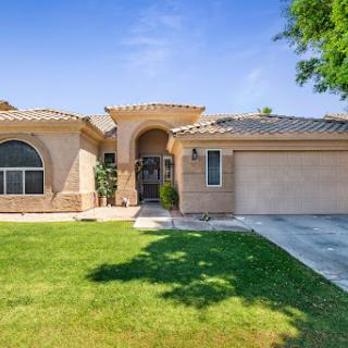 A beautiful single-story home with a well-maintained front yard under a clear blue sky.