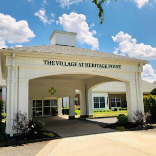 The entrance to The Village at Heritage Point, showcasing a welcoming architectural design under a clear blue sky.