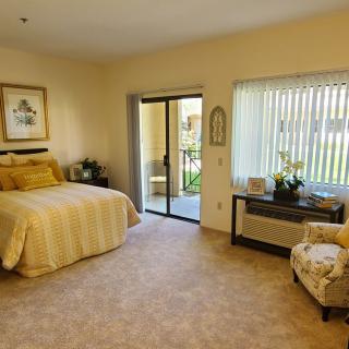 A cozy bedroom with a large bed, comfortable chair, and natural lighting from the window.