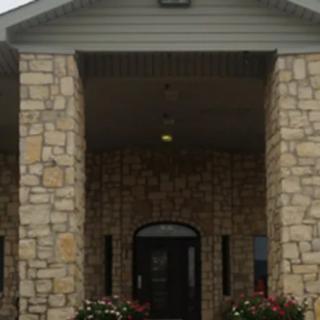A stone building entrance with columns and flowers.