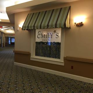 A hallway with a window displaying a sign for 'Emily's' under a striped awning.