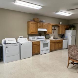 A multifunctional room featuring a kitchen area with appliances and laundry machines.