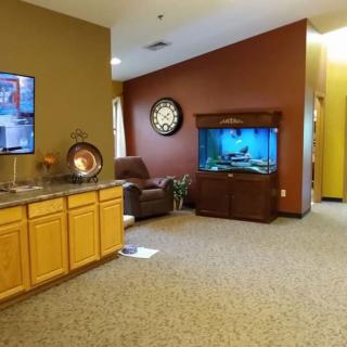 A cozy living room with a television, fish tank, and armchair.