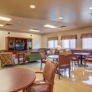 Spacious and well-lit living room with comfortable seating, tables, and a television.