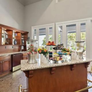 A spacious kitchen with wooden cabinets, a granite island counter, and bright natural lighting from large windows.