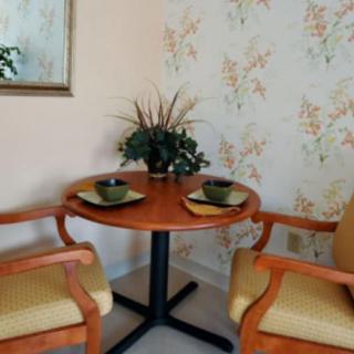 A cozy dining nook with a round wooden table, two chairs, and decorative place settings.
