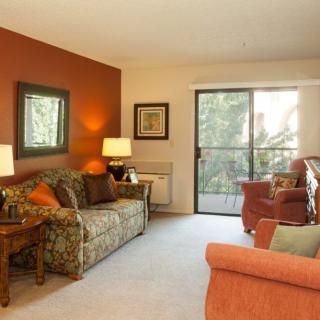 A cozy living room with warm tones, featuring a sofa, chairs, and decorative lamps.