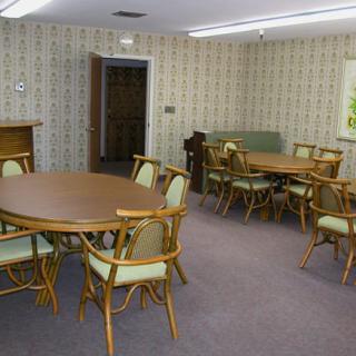 A vintage dining room with retro furniture, featuring round tables and patterned wallpaper.