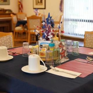 A dining table set with cups, plates, and a patriotic centerpiece.
