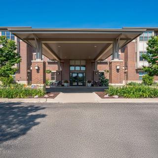 A modern building entrance with a large canopy and landscaped surroundings.
