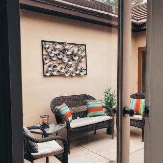 A cozy patio area with wicker furniture, colorful cushions, and decorative wall art.
