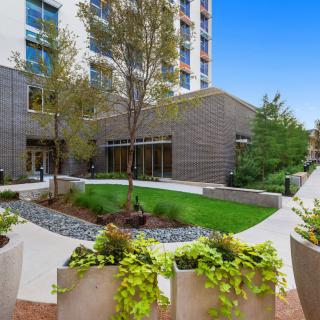 A modern apartment complex featuring lush greenery and a well-maintained outdoor courtyard.