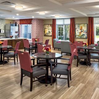 A modern dining area with neatly arranged tables and chairs, featuring stylish decor and large windows.