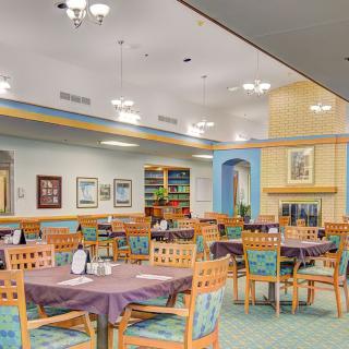 A cozy dining area with neatly arranged tables and chairs, warm lighting, and tasteful decor.